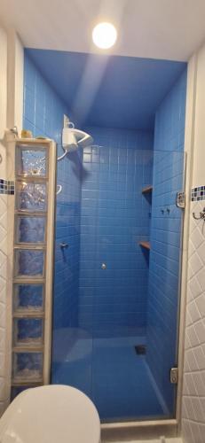 a bathroom with a blue tiled shower with a toilet at Ap107 Espaço Aconchegante com Toque Mediterrâneo in Vitória