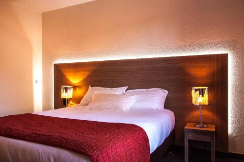 a bedroom with a large bed with a wooden headboard at Hotel Les Amandiers in Tournon-sur-Rhône