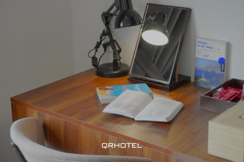 a desk with a lamp and books and a mirror at QR Hotel Dalat in Xuan An