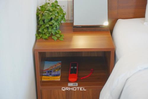 a wooden night stand with a remote control on it at QR Hotel Dalat in Xuan An