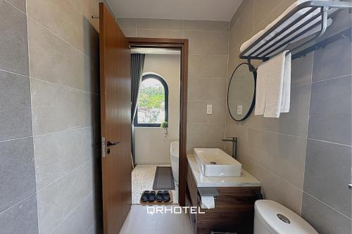 a bathroom with a sink and a toilet and a mirror at QR Hotel Dalat in Xuan An