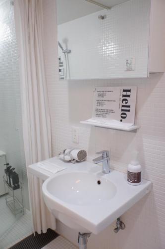 a white bathroom with a sink and a mirror at TAKETO STAY Osakajo in Osaka