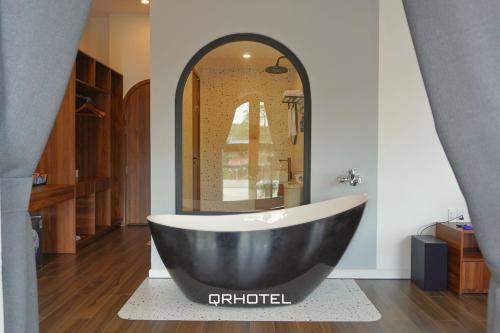 a large black tub in a bathroom with a mirror at QR Hotel Dalat in Xuan An