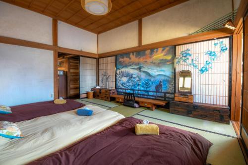 una stanza con due letti e un dipinto sul muro di Yamabo Inn 古民家 Traditional Japanese Home a Ōmachi