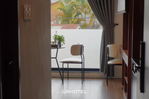 a room with a table and chairs in front of a window at QR Hotel Dalat in Xuan An