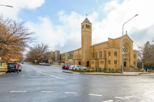a large church with a clock tower on a street at Luxury Griffith Retreat steps from Iconic Manuka - Hosted by Canstay in Griffith