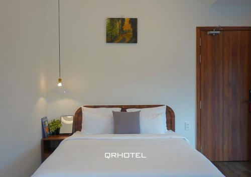a bedroom with a bed with white sheets and a wooden cabinet at QR Hotel Dalat in Xuan An