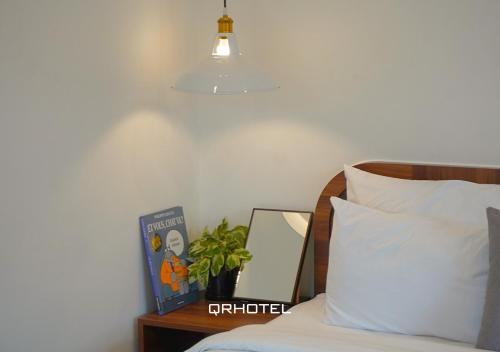 a bedroom with a bed and a potted plant and a lamp at QR Hotel Dalat in Xuan An