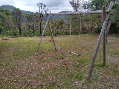 an old swing set in a field with trees at Sítio topo do Vale in Sabará