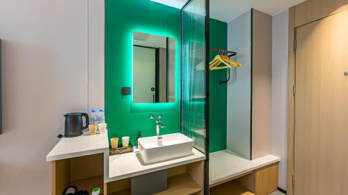 Un baño verde con lavabo y espejo. en Urban Garden Hotel, en Xi'an