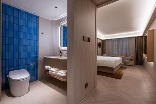 a bathroom with a bed and a sink and a toilet at Orange Crystal Qingdao Taidong Pedestrian Street Yan'an Third Road Hotel in Qingdao