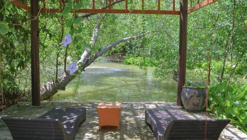a covered area with a table and chairs next to a river at Natural Place in Ban Khan Ham