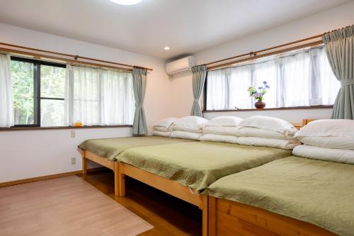 two beds in a room with windows at Nasu Hanbok in Nasu-yumoto