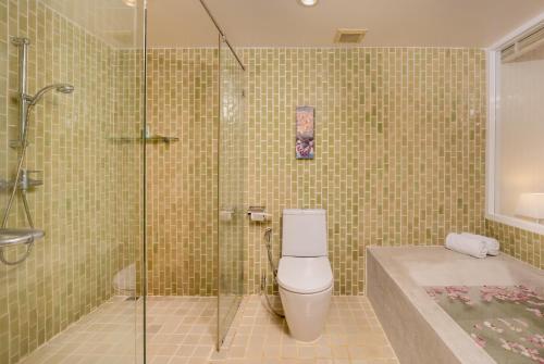 a bathroom with a shower and a toilet and a tub at The Briza Beach Resort, Khao Lak SHA Extra Plus in Khao Lak