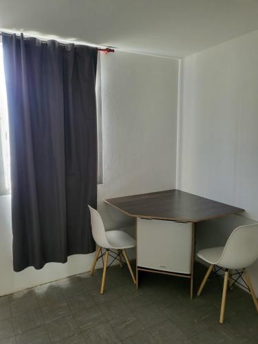 a desk and two chairs in a room with a curtain at SLC San Martín 3 in San Luis