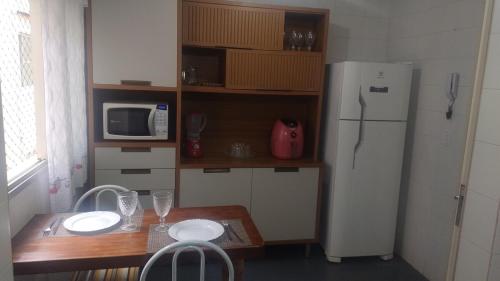 a kitchen with a table and a white refrigerator at 2 bedrooms 2 bathrooms shopp beach wifi in Vila Velha
