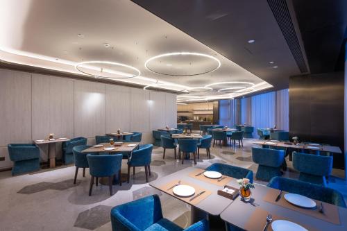 a dining room with tables and blue chairs at Orange Crystal Qingdao Taidong Pedestrian Street Yan'an Third Road Hotel in Qingdao