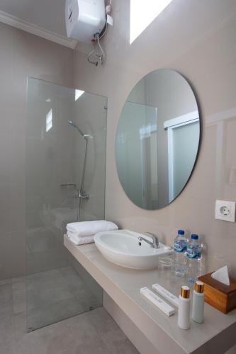 a white bathroom with a sink and a mirror at Rumah Wikan Bukit-Uluwatu in Uluwatu