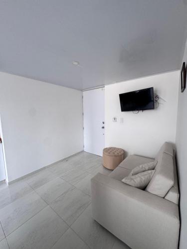 a white living room with a couch and a tv at Apartamento Caribe Coveñas 102 in Coveñas
