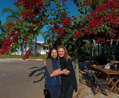 two women hugging in front of a tree with flowers at Refúgio Nossa Senhora Auxílio dos Cristãos in Guapé