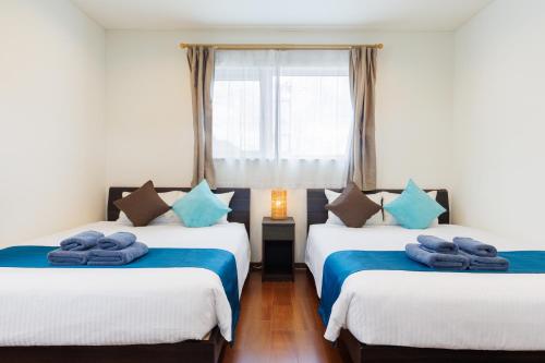 two beds in a room with blue towels on them at Kahoo House in Nago