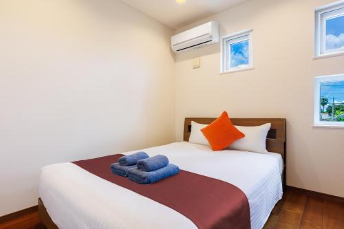 a bedroom with a bed with blue towels on it at Kahoo House in Nago