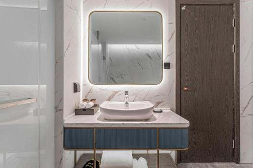 a bathroom with a sink and a mirror at Grand Madison Wuhan Hankou on the Bund in Wuhan