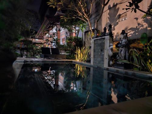 a swimming pool at night with people standing around it at Nick's Homestay in Ubud