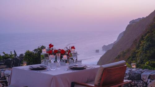 a table with a white table cloth and red flowers at Alila Villas Uluwatu in Uluwatu