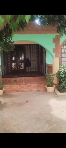 a black dog sitting behind the gate of a house at Afonta's Greenhouse Retreat in Daranka