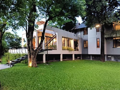 a building with a tree in front of a yard at Chombua MaeWang ชมบัว in Chiang Mai