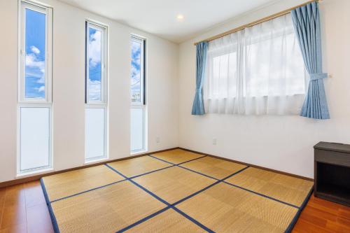 a room with white walls and windows with blue curtains at Kahoo House in Nago