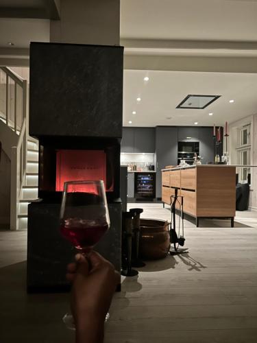 a person holding a glass of wine in front of a fireplace at Handelsmannens hus ved Otnesbrygga, Valsøyfjord in Otnes