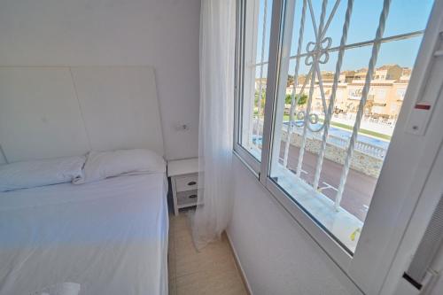 a bedroom with a bed and a large window at Soleado adosado esquinero frente a piscina in Gran Alacant