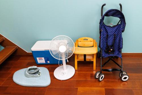 a room with a fan a chair and a table at Kahoo House in Nago