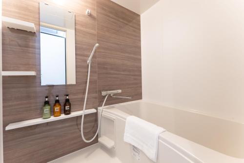 a bathroom with a bath tub and a sink at Tabist HOTEL UENO 39 in Tokyo