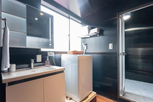 a small bathroom with a sink and a refrigerator at Tabist HOTEL UENO 39 in Tokyo