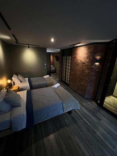 a bedroom with two beds and a brick wall at Solar Deluxe Arequipa in Arequipa
