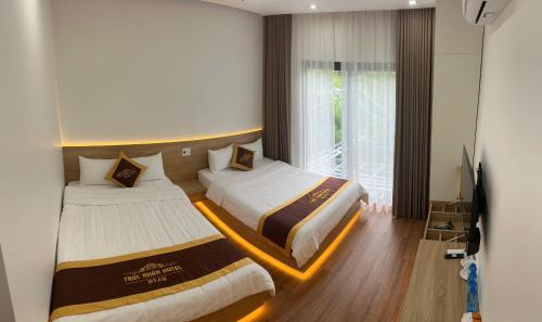 um quarto de hotel com duas camas e uma televisão em Trúc Nhân Hotel em Dồng Văn