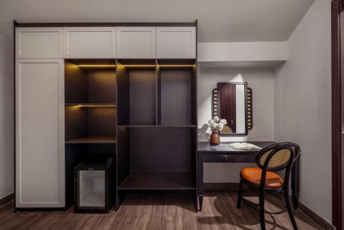 a room with a desk and a chair and a mirror at ELC Boutique Hoi An Hotel in Hoi An