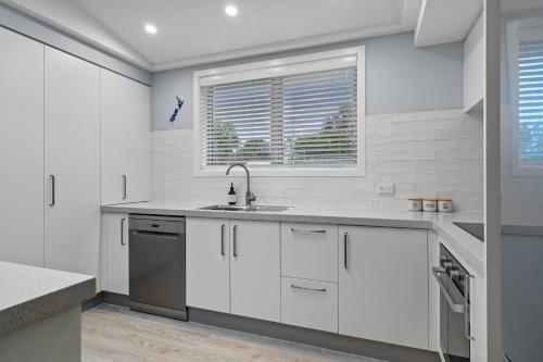 eine Küche mit weißen Schränken und einer Spüle in der Unterkunft Beach Road Oasis - Waikawa Holiday Home in Picton