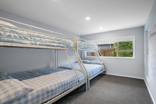 zwei Etagenbetten in einem Zimmer mit Fenster in der Unterkunft Beach Road Oasis - Waikawa Holiday Home in Picton