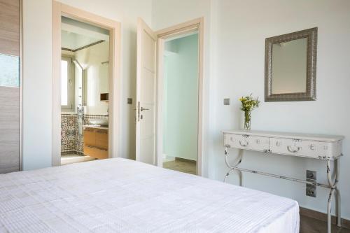 a white bedroom with a bed and a mirror at Afrodite Luxury Villa in Svoronata