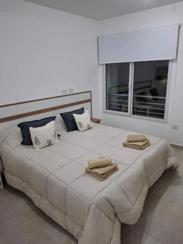 a large white bed with pillows and a window at Departamento Pia in Neuquén