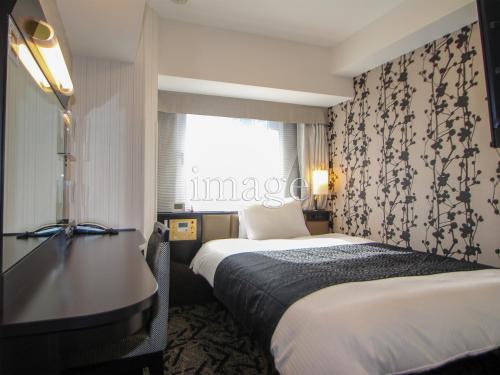 a hotel room with two beds and a desk at APA Hotel Morioka Ekimae in Morioka
