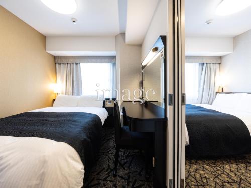 a hotel room with two beds and a mirror at APA Hotel Morioka Ekimae in Morioka