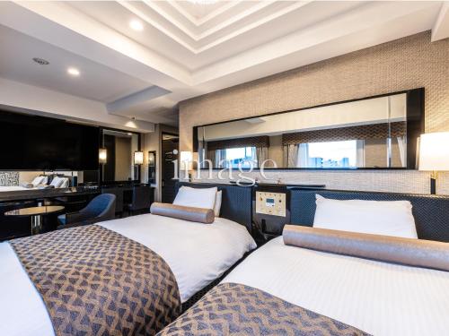 a hotel room with two beds and a desk at APA Hotel Morioka Ekimae in Morioka