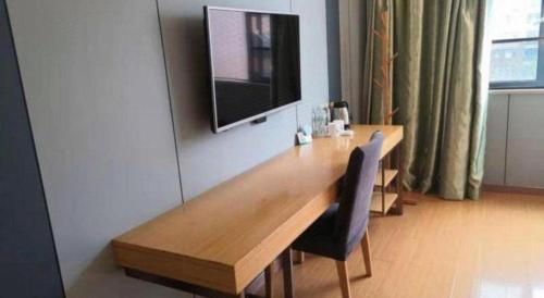 a wooden table with a television on a wall at GreenTree Inn Shangrao Qianshan hekou old town Xinjiang longting shell hotel in Shangrao