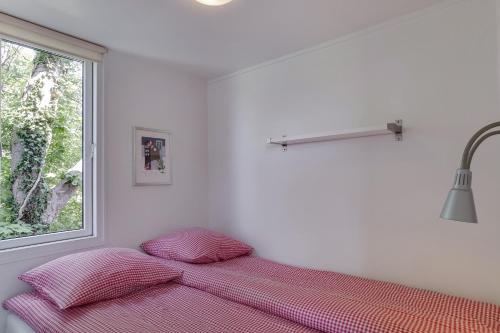 a bed in a white room with a window at Ølholm Cottage in Stege