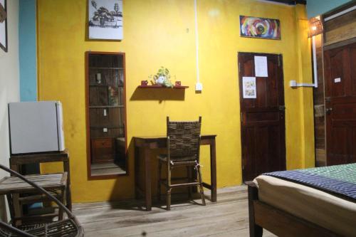 a room with a yellow wall with a table and a chair at Fish Island Bungalows in Kampot